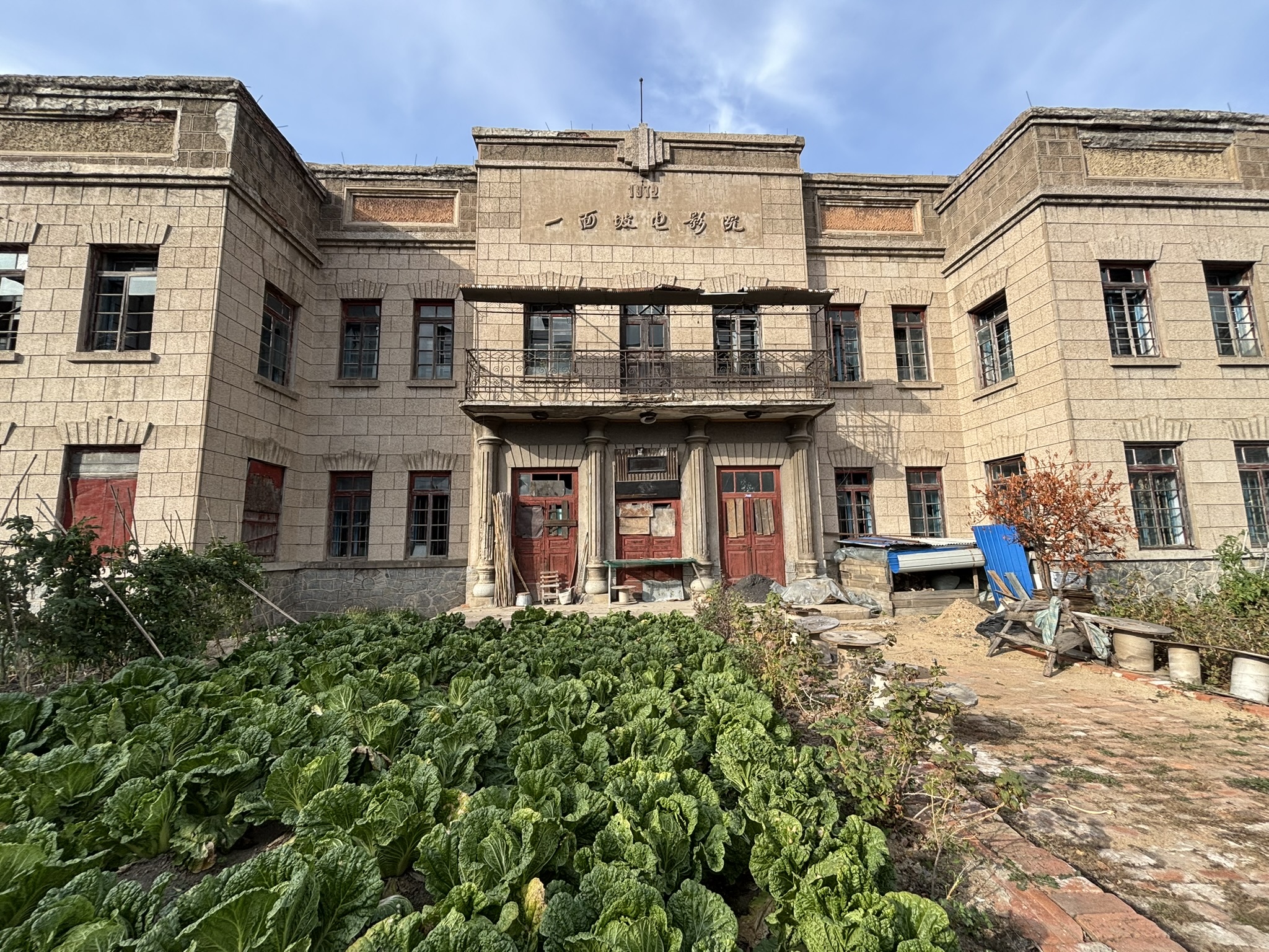 Vegetables grow in front of an abandoned movie theater in Yimianpo, in China